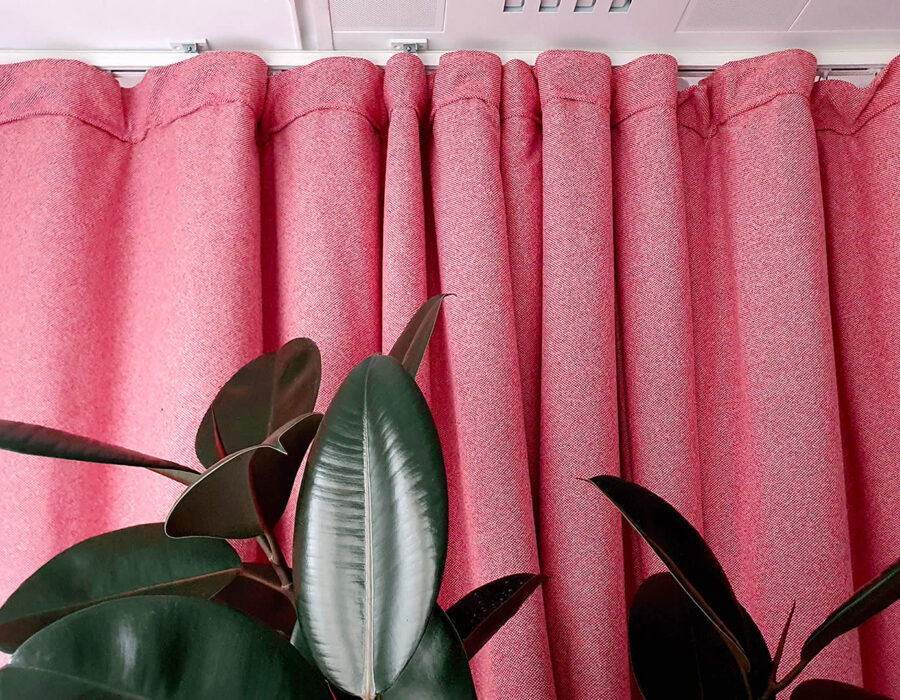 Cortina acústica rosa de tejido grueso con una planta verde en primer plano, interior moderno